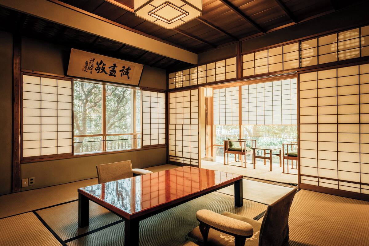 Une pièce de style japonais traditionnel, avec un sol recouvert de tatamis, une petite table en bois et des paravents en papier de riz (shoji).