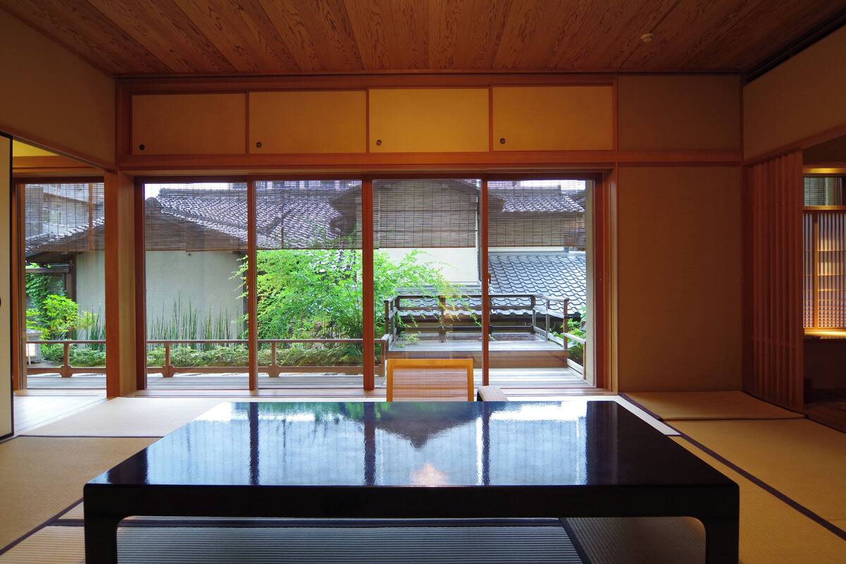 Une pièce de style japonais traditionnel, avec un sol recouvert de tatamis, une table basse et des portes coulissantes donnant sur un jardin.