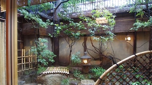 A traditional Japanese garden with a bamboo bridge, a stone lantern, and a small pond. - Hiiragiya (Kyoto)