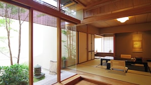 A traditional Japanese room with tatami flooring, sliding doors, and a view of a garden. - Hiiragiya (Kyoto)