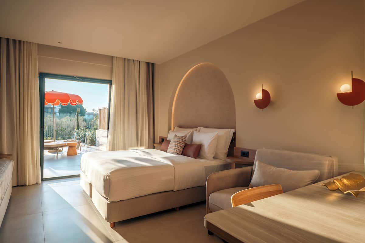 Une chambre d’hôtel moderne dotée d’un grand lit, d’un canapé, d’une table à manger et offrant une vue sur l’extérieur.