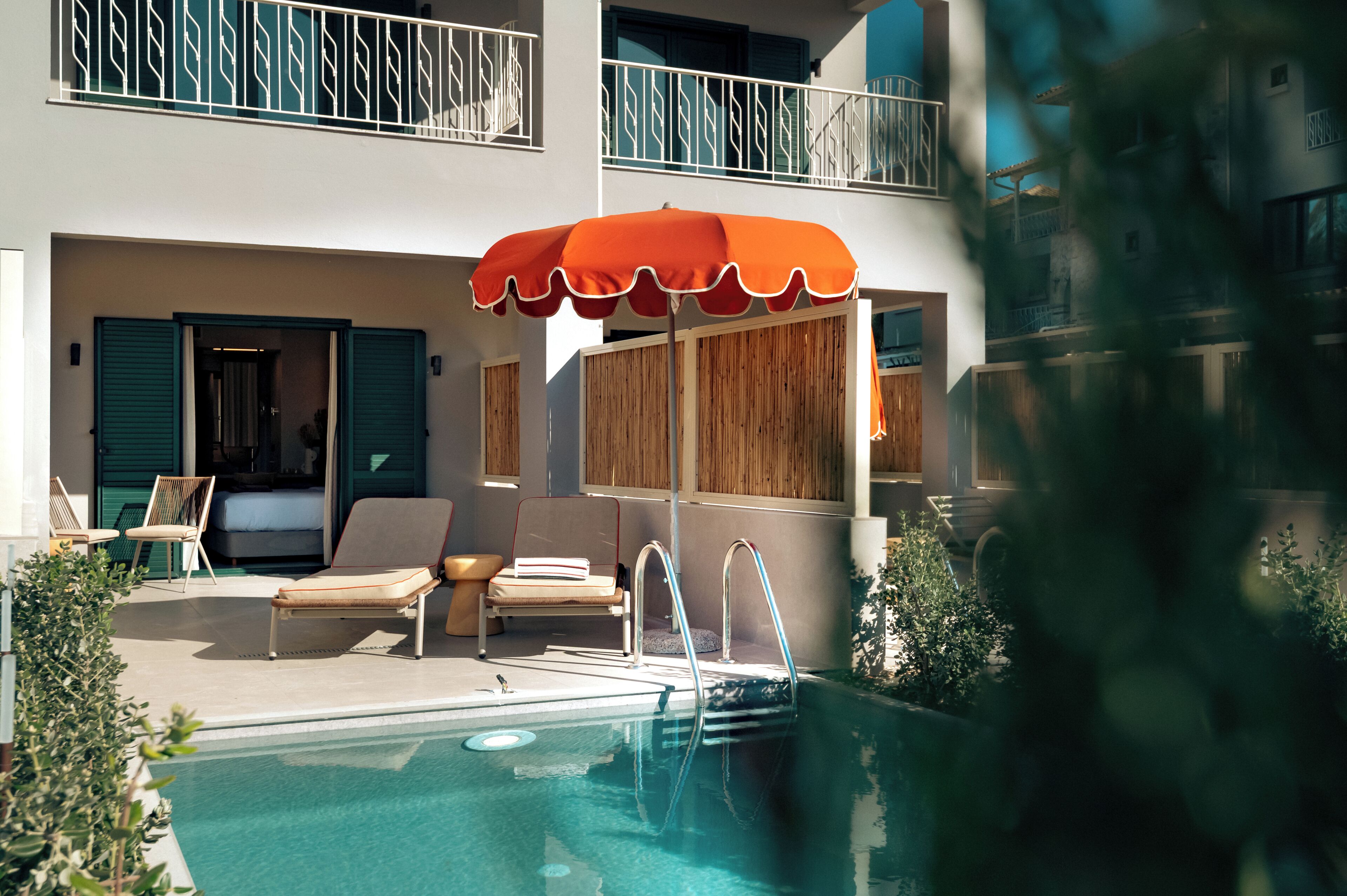 Un área de piscina con sillas de descanso, una sombrilla y una terraza de madera.