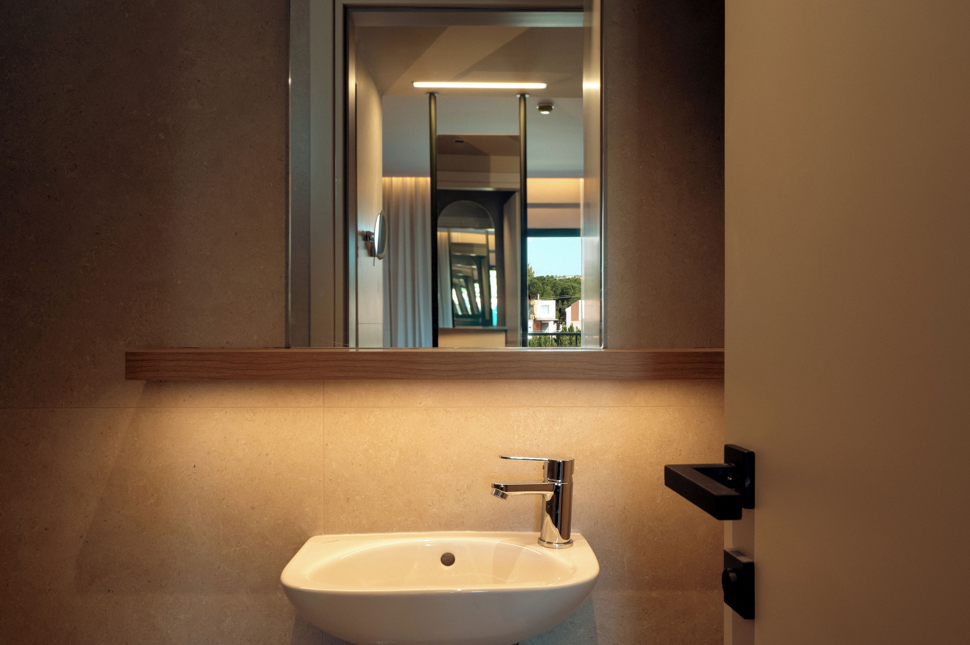 A bathroom with a white sink, a mirror, and a light fixture above the mirror.