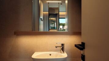A bathroom with a white sink, a mirror, and a light fixture above the mirror.