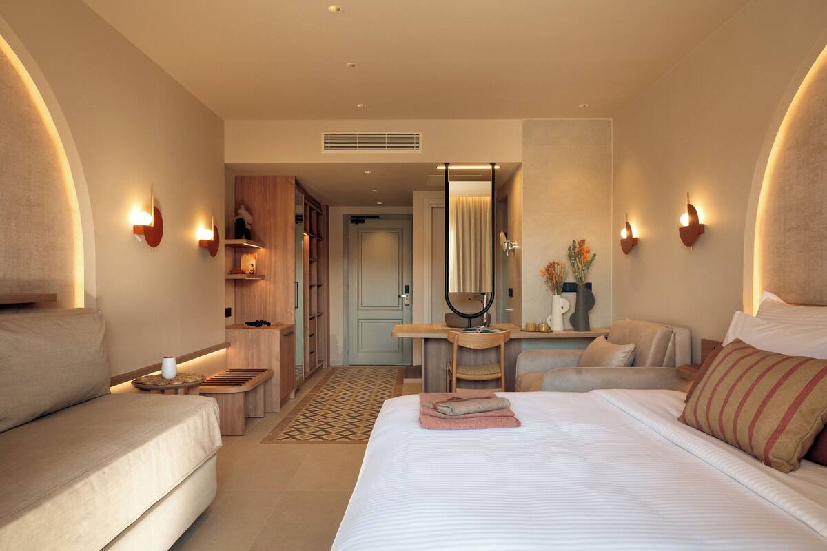 Une chambre d’hôtel moderne équipée d’un lit, d’un canapé, d’un bureau et d’un miroir.