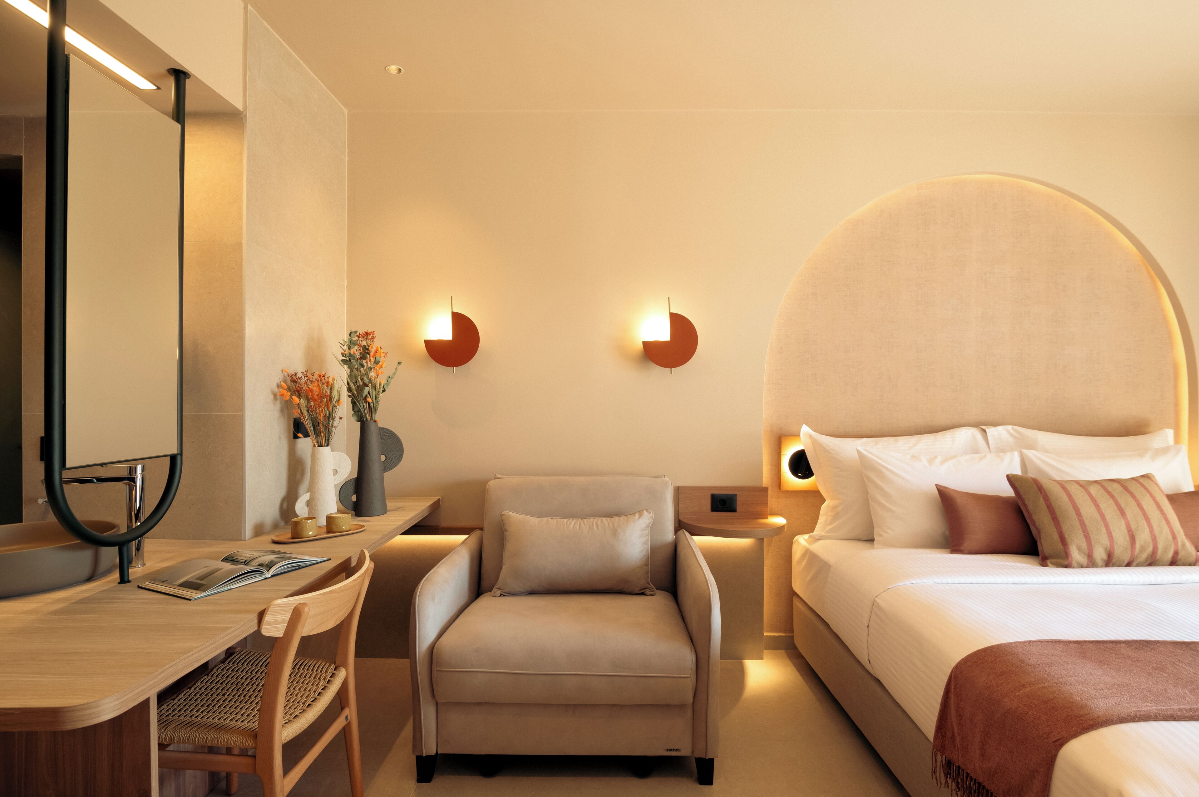 Ein modernes Hotelzimmer mit Bett, Schreibtisch, Stuhl und einem großen Spiegel.