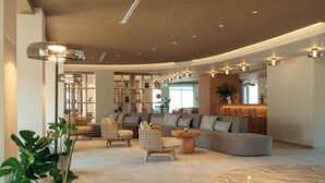 A modern living room with a sectional sofa, two armchairs, a coffee table, and a bookshelf. - Zeus Eleva Kassandra Lagoon (Kassandra)