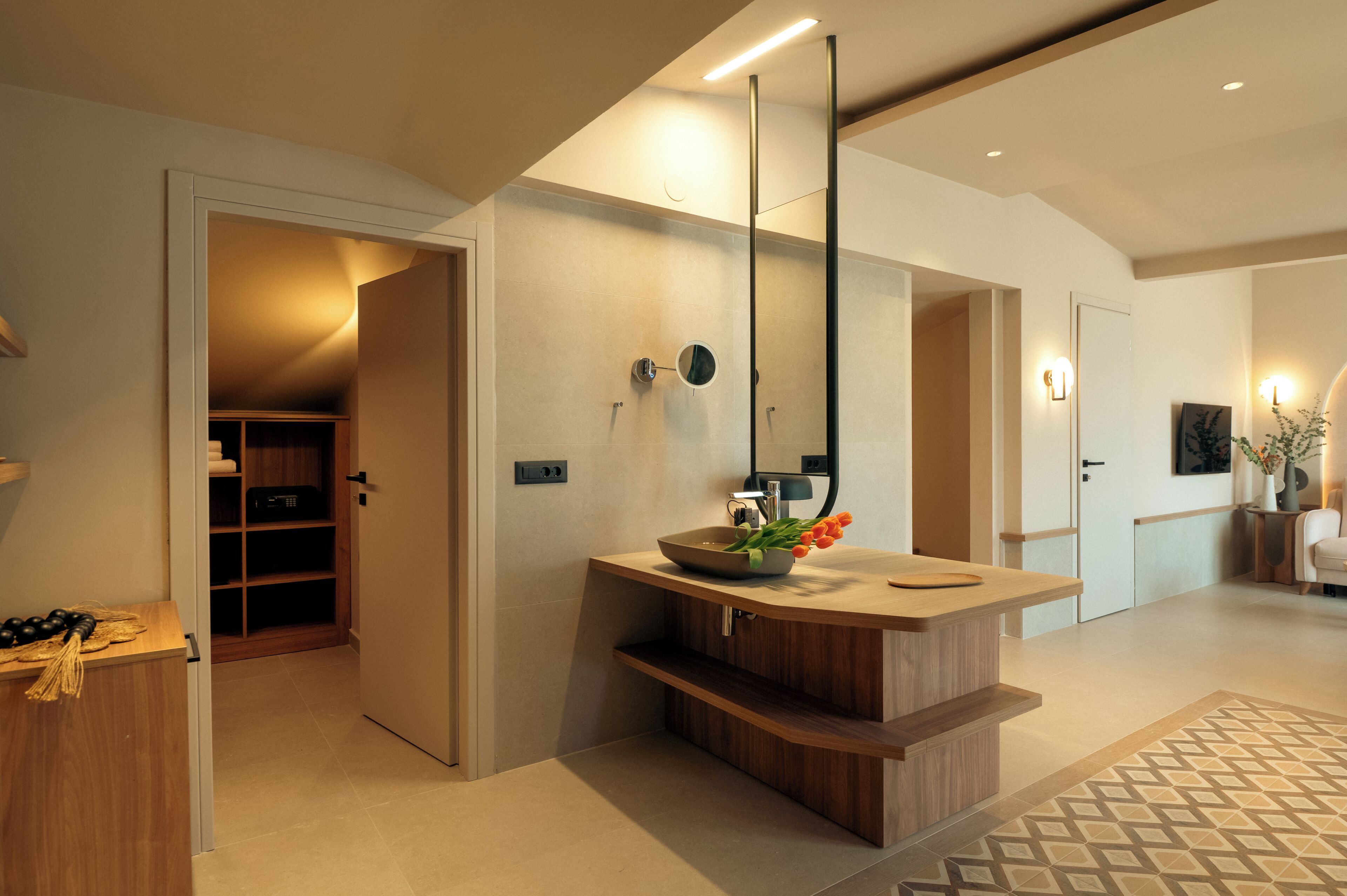 A modern bathroom with a wooden vanity, a mirror, and a sink. There is a towel rack and a shower area visible.