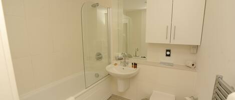 Un baño moderno con ducha envuelta en vidrio, un lavabo blanco, un inodoro y un mueble sobre el lavabo.
