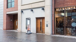 A storefront with a sale sign, a wooden door, and a brick wall.