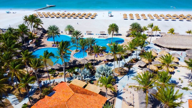 A resort with multiple swimming pools, palm trees, and a beach area. - Sunsol Punta Blanca (San Pedro)