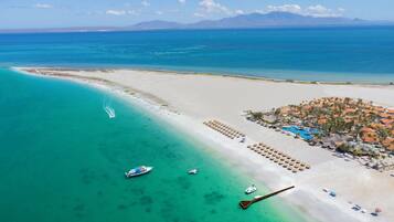 Relax on the pristine beach with lounge chairs and umbrellas, enjoy water activities from the docked boat, and take in the breathtaking views of the surrounding mountains.