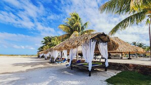 A beach with thatched-roof huts, white curtains, and lounge chairs. - Sunsol Punta Blanca (San Pedro)