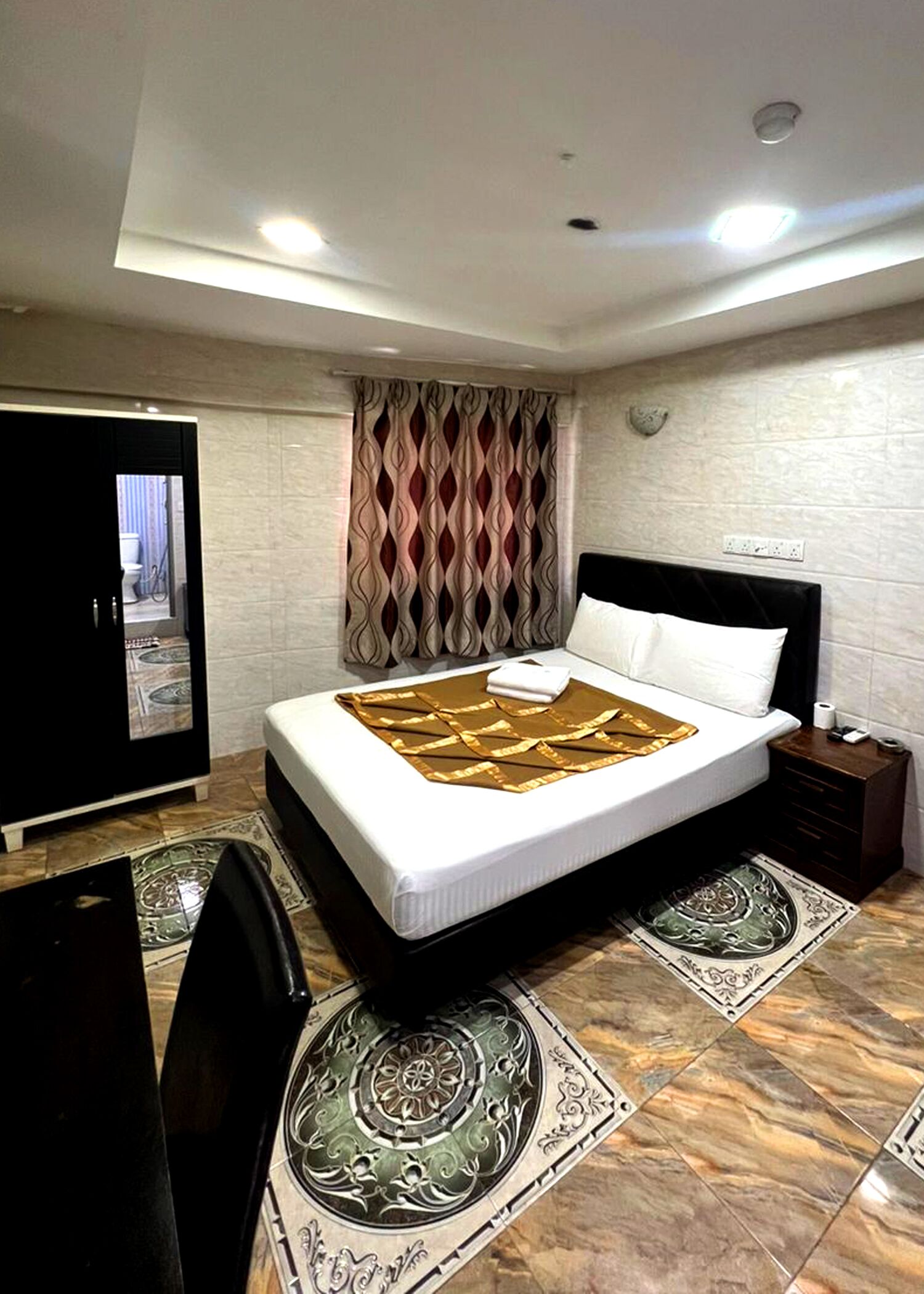 Habitación de hotel con cama, escritorio, armario y baño visible a través de una puerta abierta.