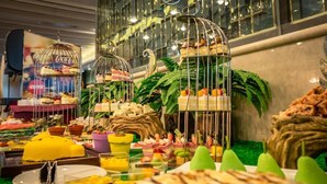 Un bufé con diversos alimentos exhibidos en jaulas decorativas y sobre una mesa.