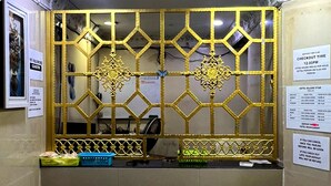 A reception desk with a decorative golden partition, a blue basket, and a white sign indicating checkout time. - Kajang Star Hotel (Kajang)