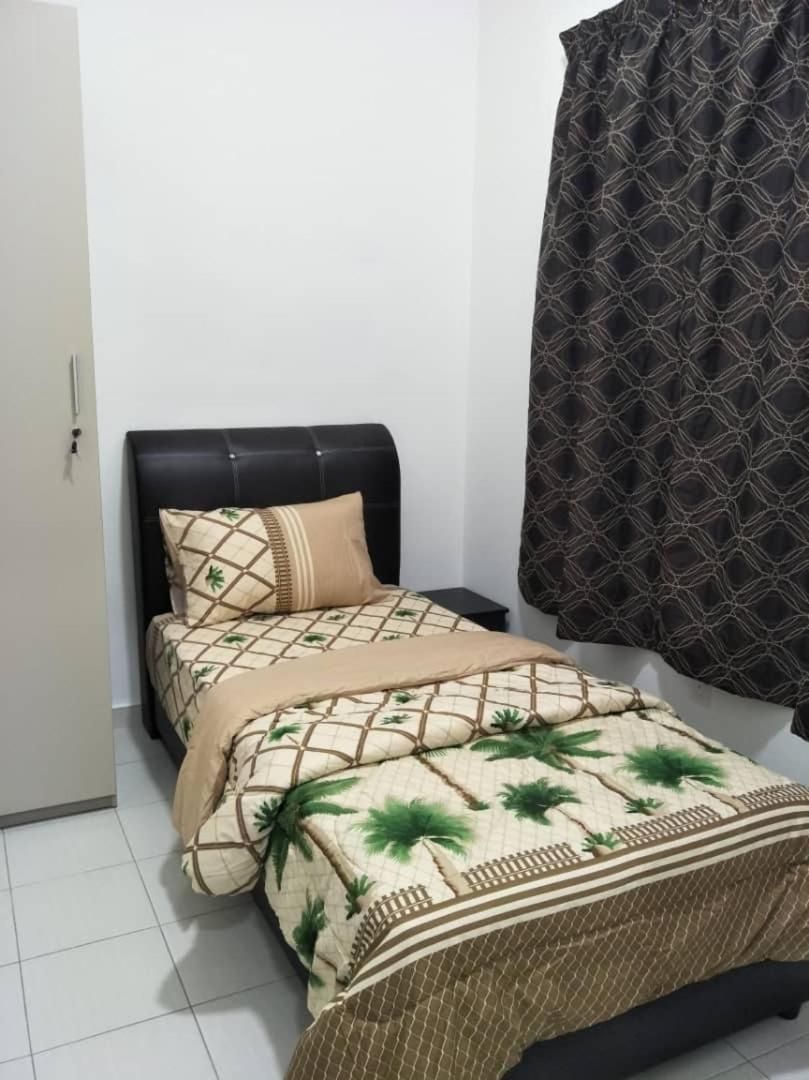 A bed with a patterned bedspread, a black headboard, and a single pillow.