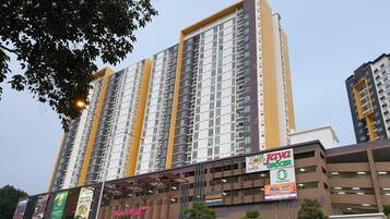 Un edificio de gran altura con varios pisos, rodeado de comercios, incluyendo una tienda de comestibles y una farmacia.