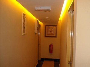 A hallway with a ceiling-mounted air conditioner, a framed picture on the wall, and a fire extinguisher mounted on the wall. - Hotel New Wave Nilai (Nilai)