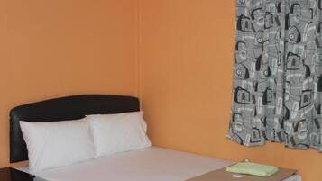 A hotel room with a bed, a nightstand, and a curtain with a pattern.
