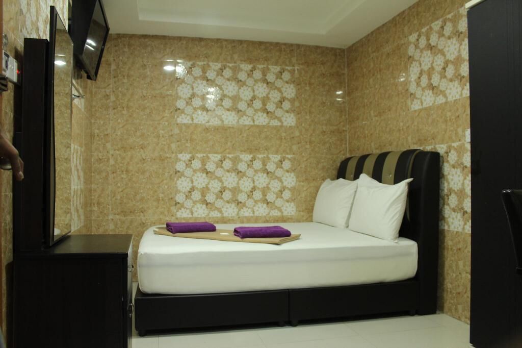 A hotel room with a bed, a TV, and a wall with a floral pattern.