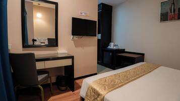 Een hotelkamer met een bed, een bureau, een stoel, een televisie en een klein tafeltje met een koffiezetapparaat.