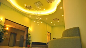 A lobby with a reception desk, a sofa, potted plants, and a decorative chandelier. - The Pavilion Hotel (Sandakan)