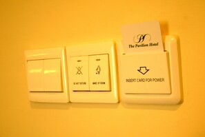 Panel de control montado en la pared con ranura para tarjetas del Hotel Pavilion, un interruptor de corriente y un botón que indica 'Limpiar Habitación'.