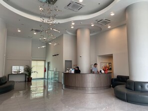 Un vestíbulo moderno con mostrador de recepción, zona de estar y techo decorativo.