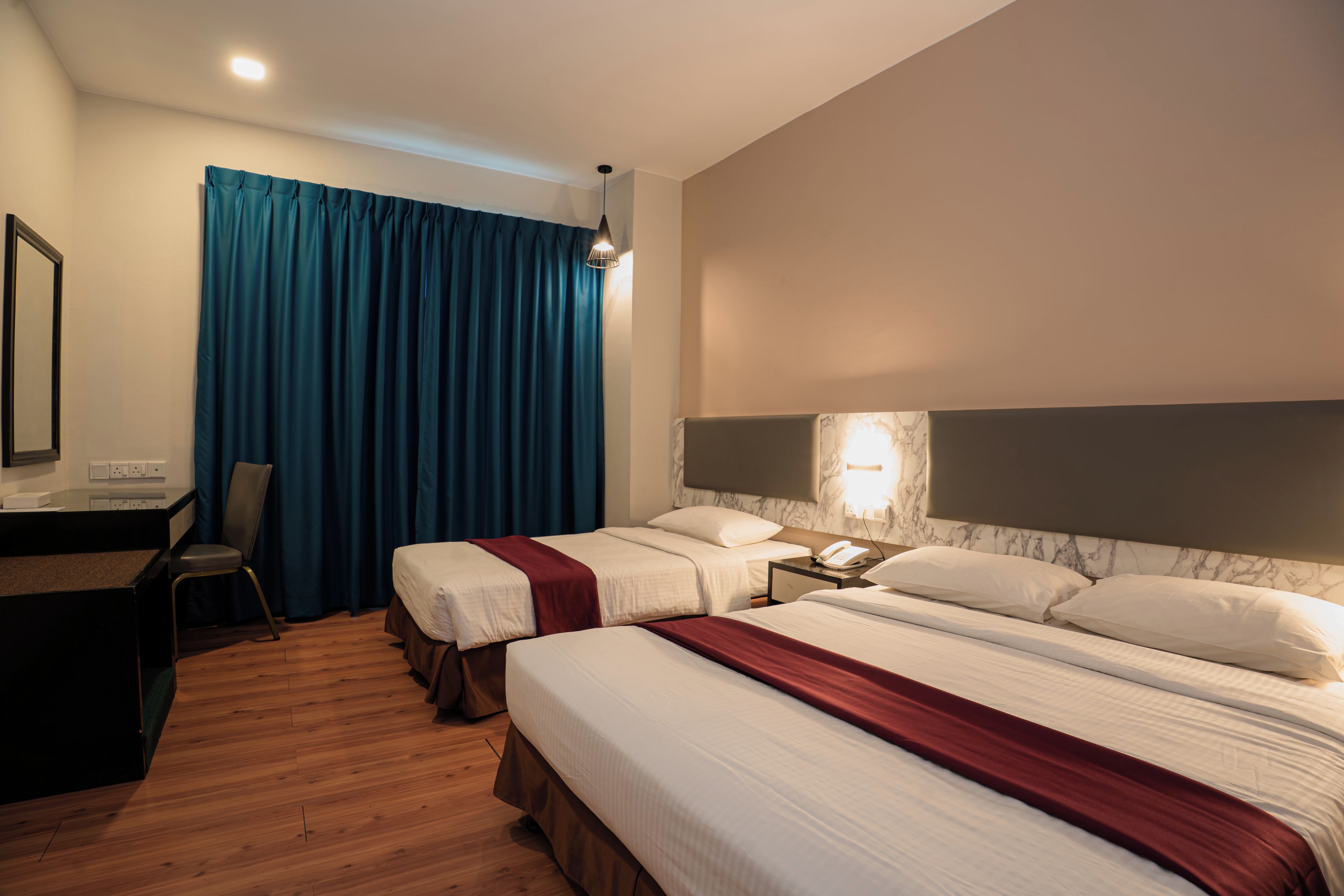 A hotel room with two beds, a desk, a chair, and a large window with curtains.