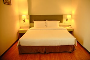A hotel room with a large bed, two bedside lamps, and a wooden floor. - The Pavilion Hotel (Sandakan)