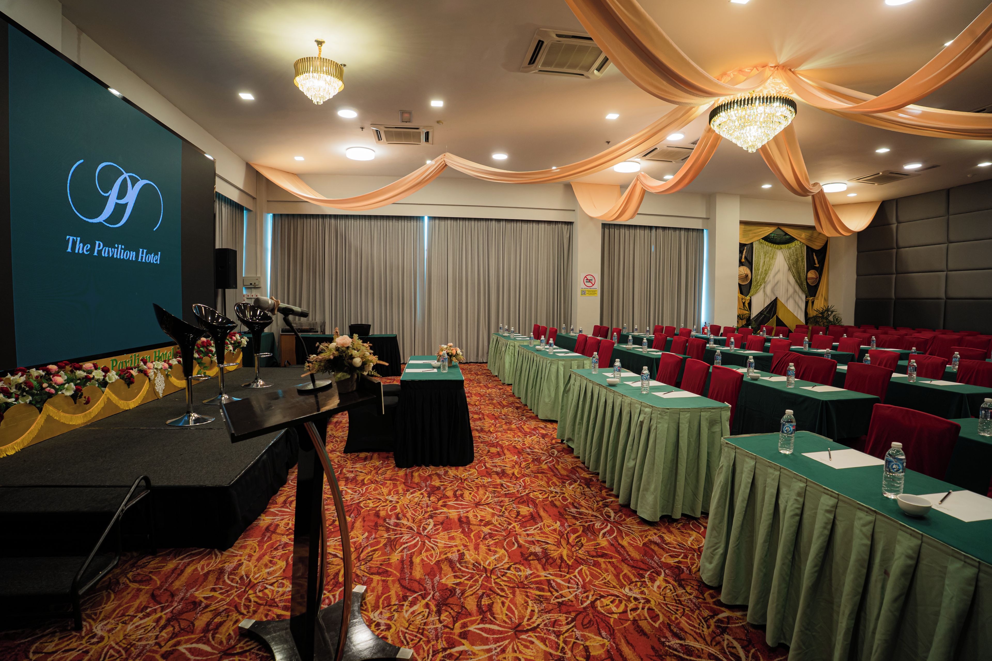 Un salón de conferencias con mesas, sillas y un escenario con un micrófono.