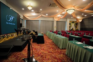 Un salón de conferencias con mesas, sillas y un escenario con un micrófono.