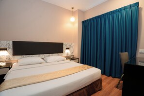 A hotel room with a large bed, a desk, a chair, and a TV. - The Pavilion Hotel (Sandakan)