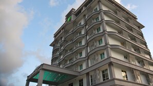 A multi-story building with balconies and a green sign on the top.