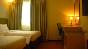 A hotel room with two beds, a desk, a chair, and a mirror.