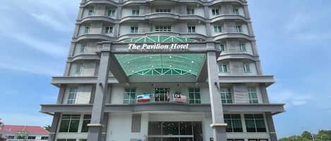 A multi-story hotel with a prominent entrance and a sign reading 'The Pavilion Hotel'.