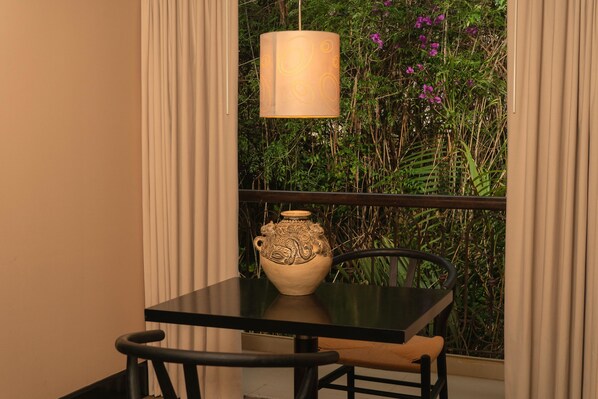 A table with a vase, a chair, and a hanging light fixture.