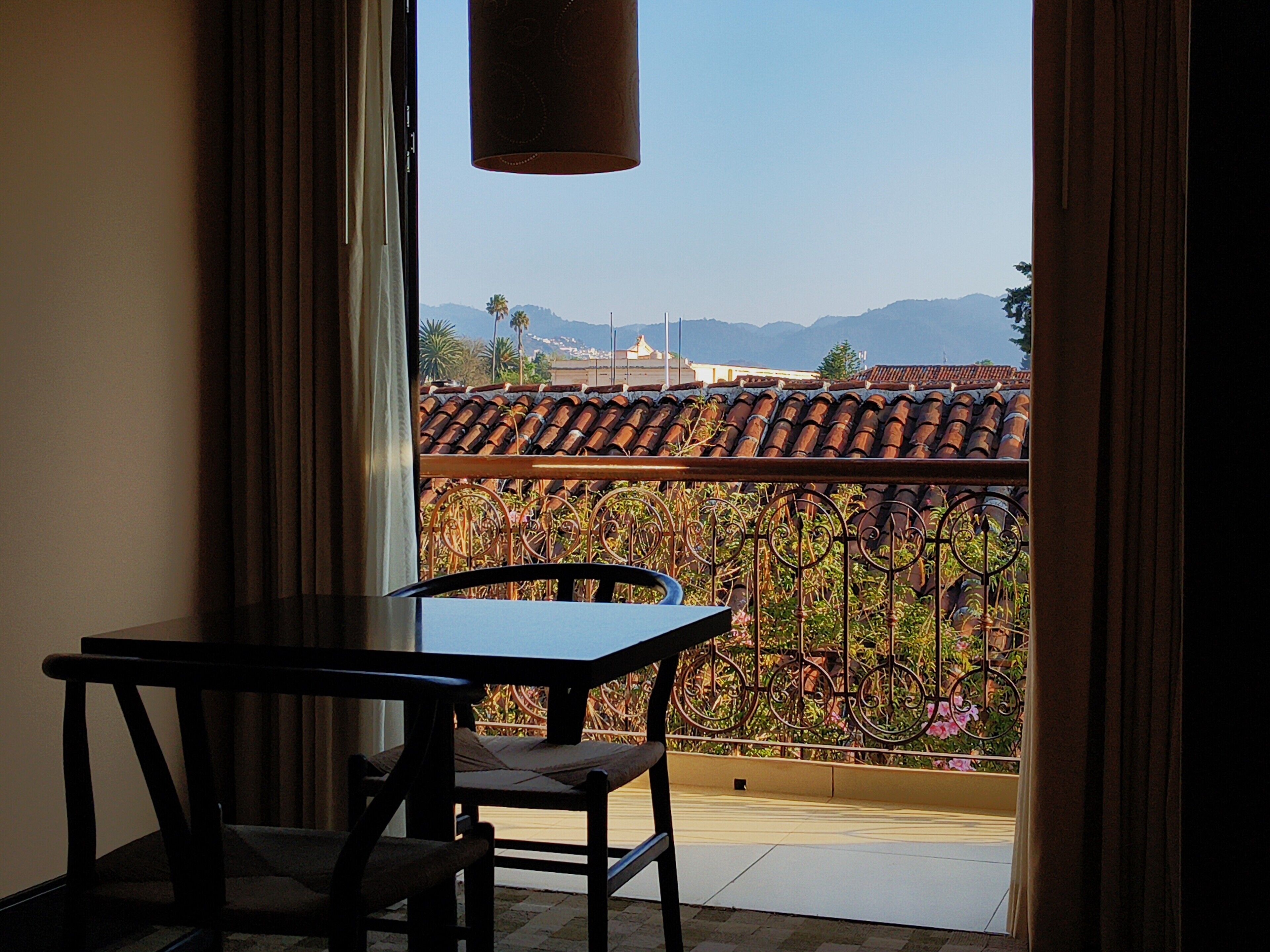 A balcony with a view of a cityscape, a table, and a chair.