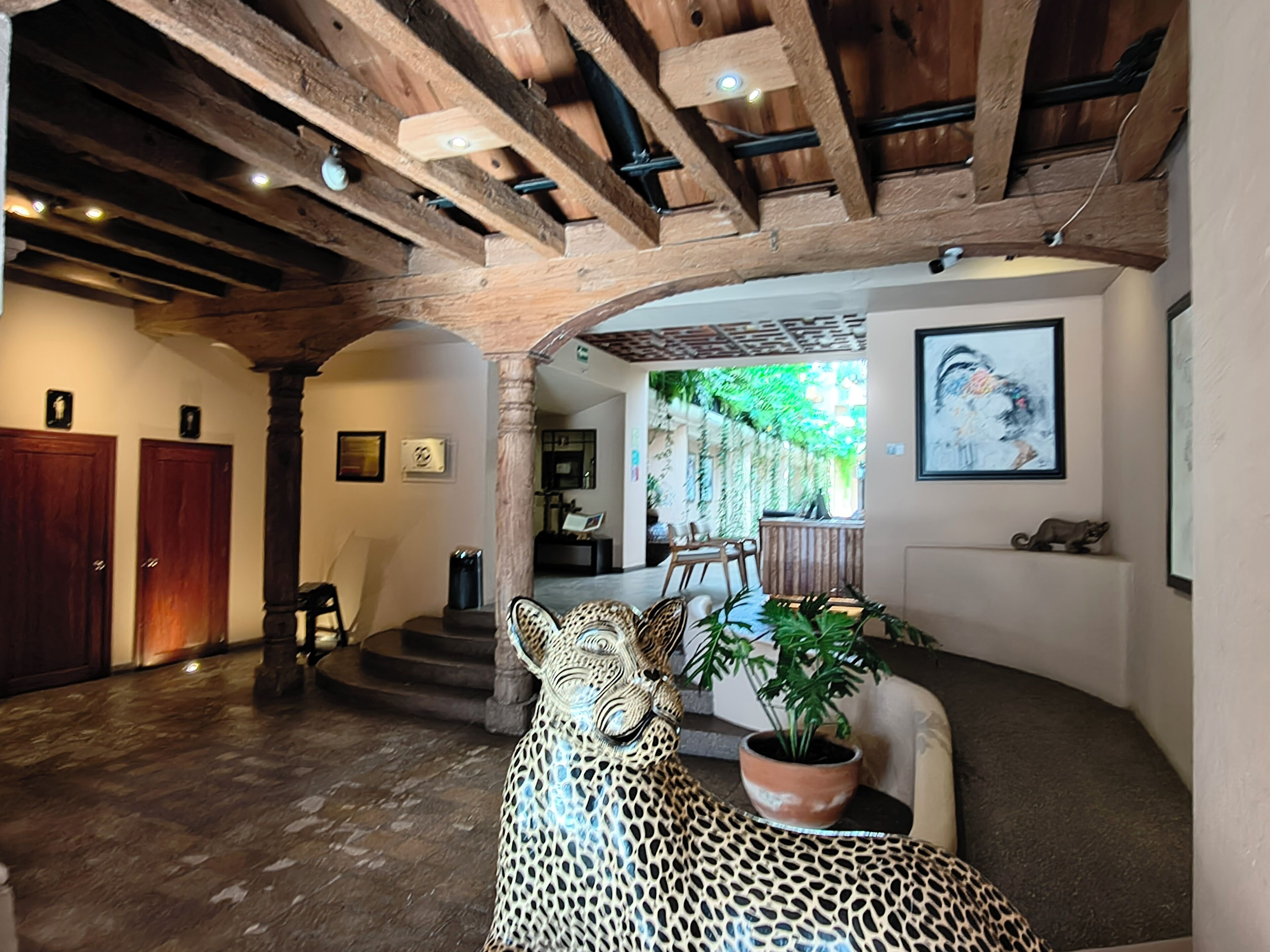 Un interior espacioso con techo de madera, una escultura de leopardo y una planta en maceta.