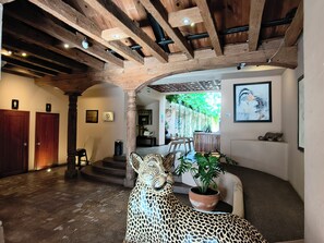 Un interior espacioso con techo de madera, una escultura de leopardo y una planta en maceta.