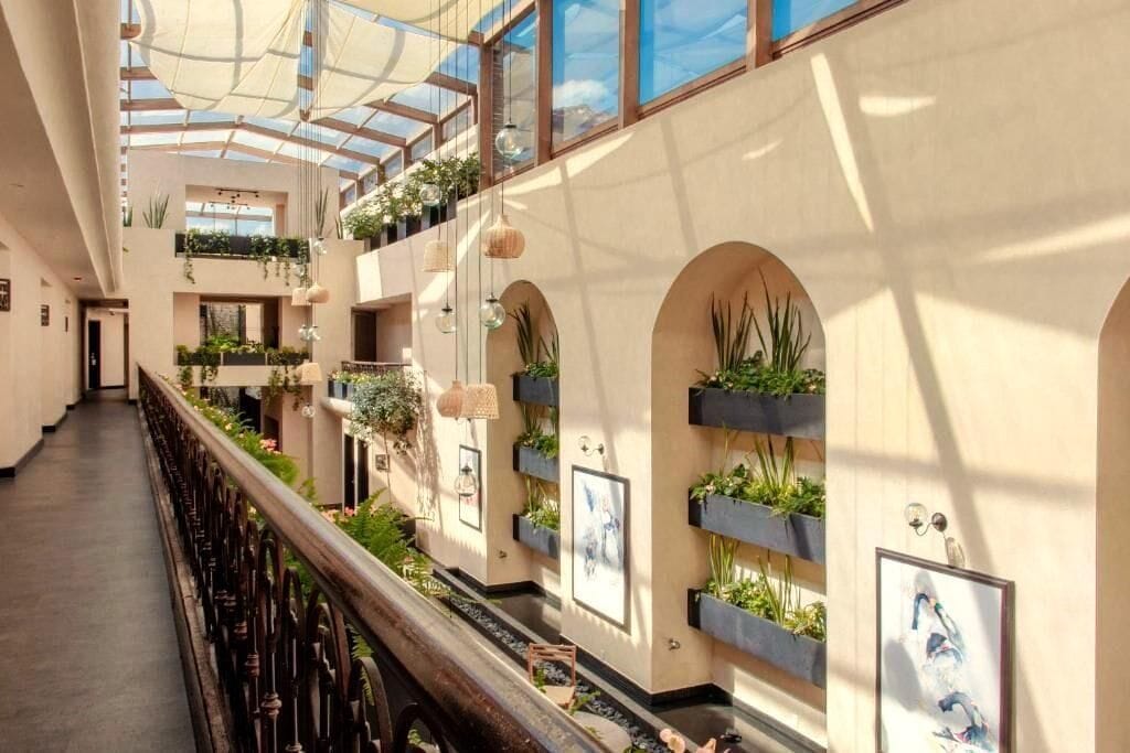A multi-level atrium with a glass ceiling, indoor plants, and artwork on the walls.