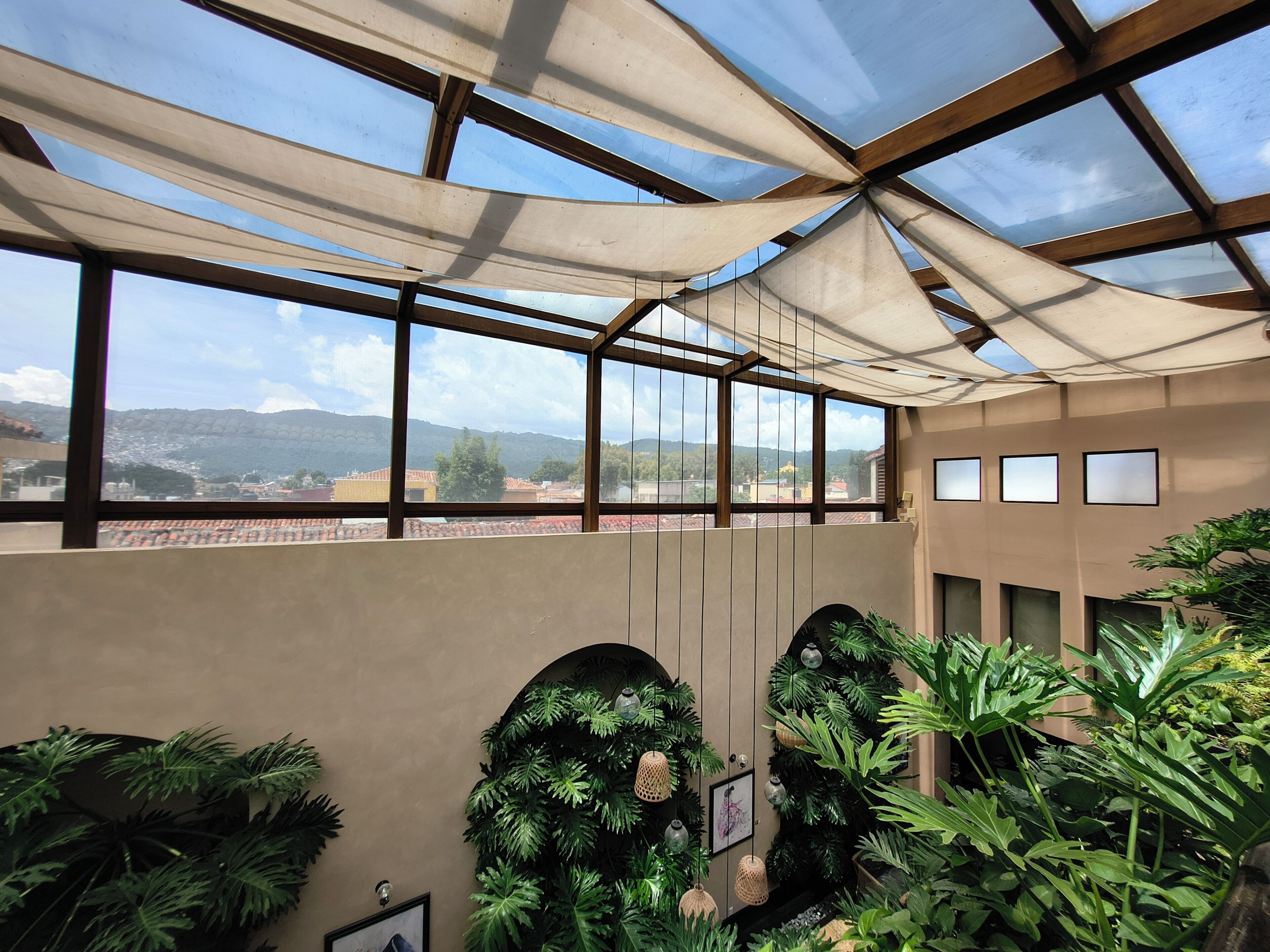 A conservatory with a view of distant mountains, large windows, and indoor plants.