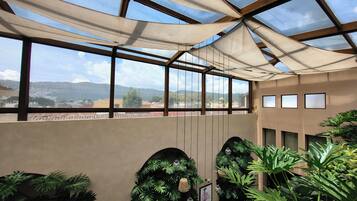 A conservatory with a view of distant mountains, large windows, and indoor plants.
