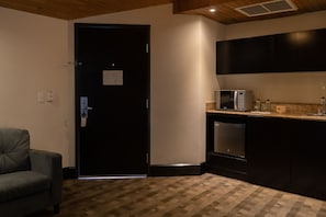 A compact kitchen with a microwave, dishwasher, and dark cabinetry.