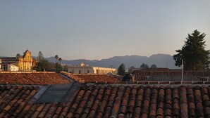 A rooftop with terracotta tiles, a church, and mountains in the background. - Casa del Alma Hotel Boutique & Spa (San Cristóbal de las Casas)
