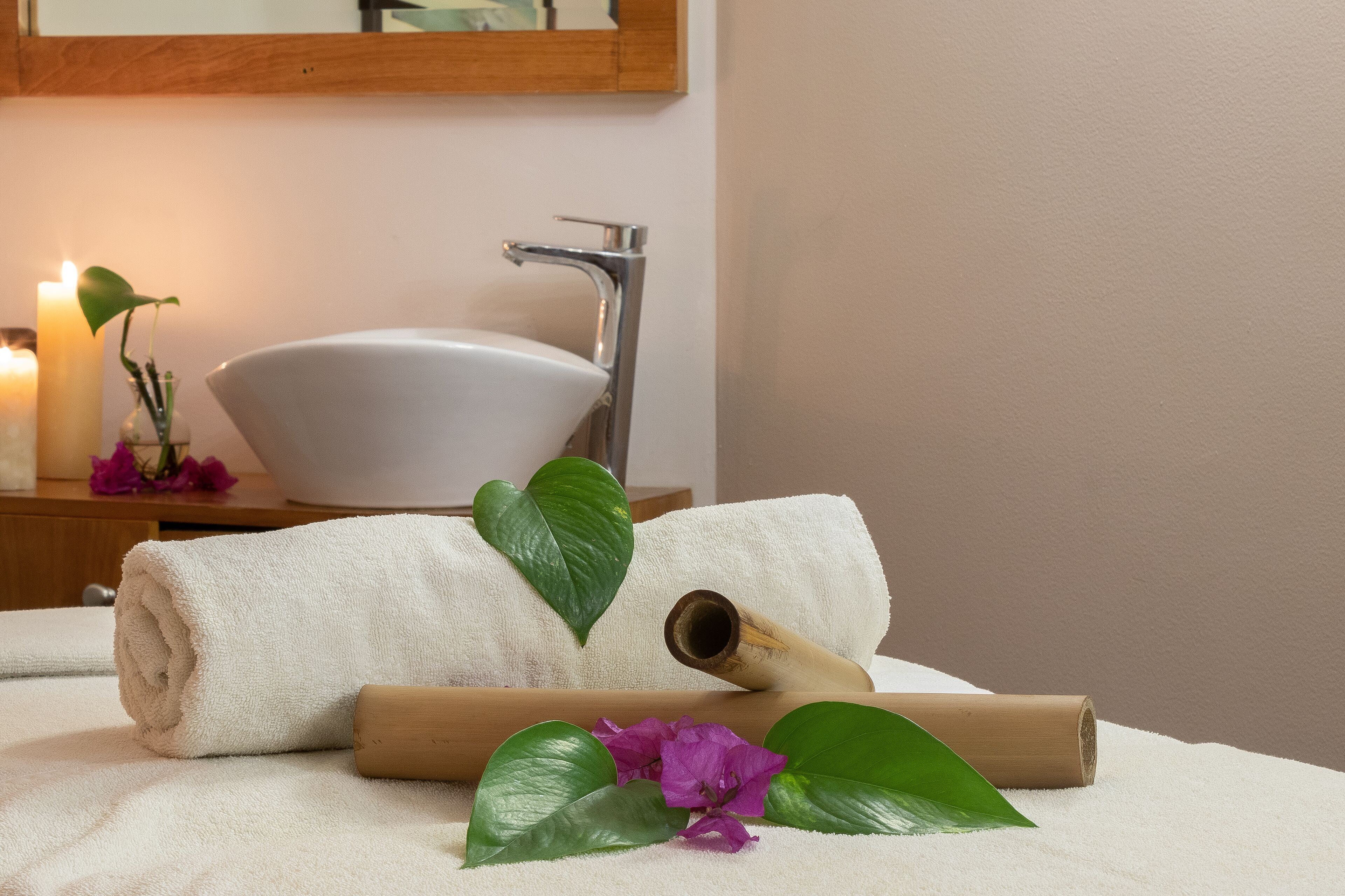 Un baño con un lavamanos blanco, un espejo y una vela.