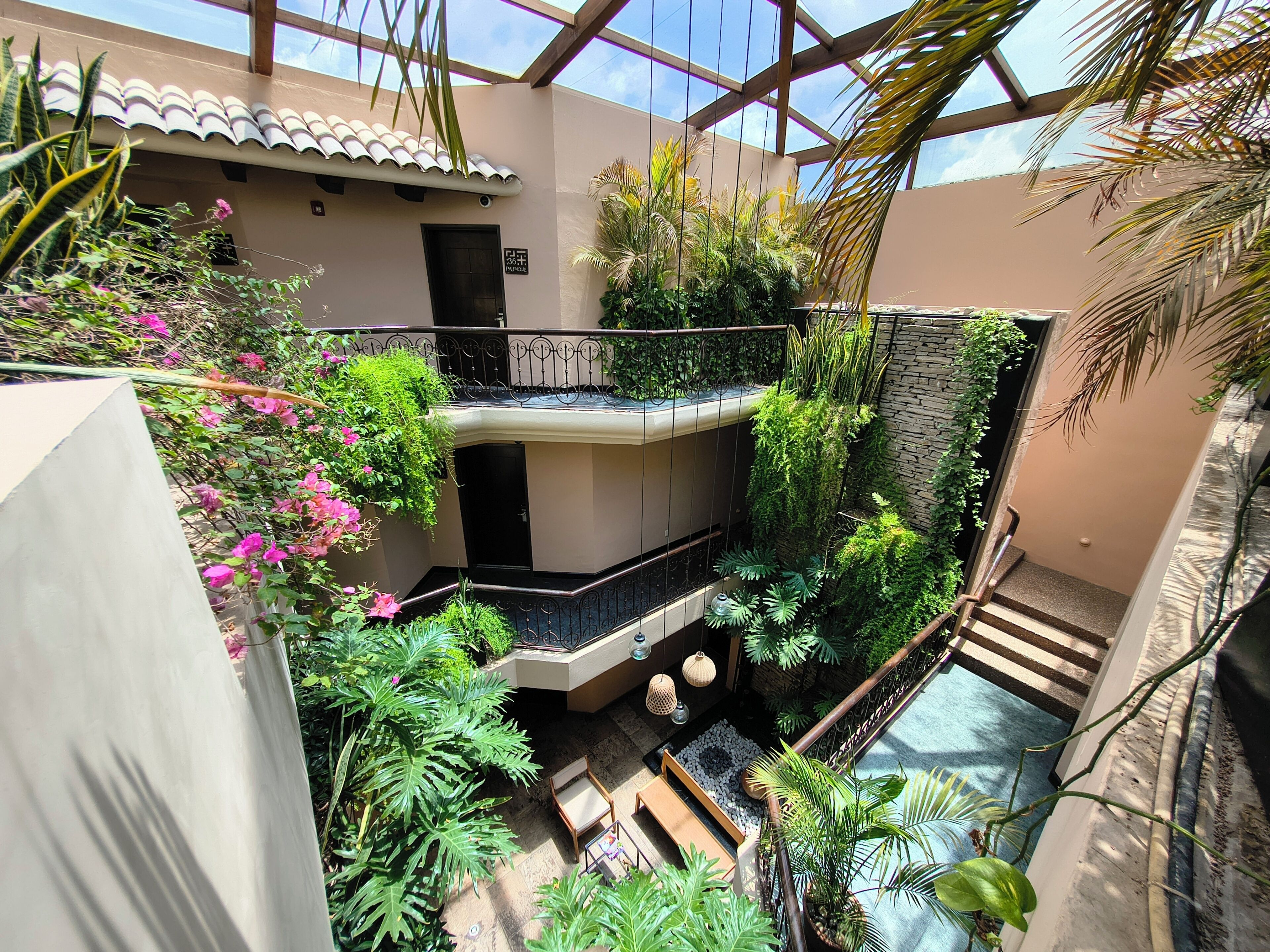 Un vestíbulo de varios niveles con abundante vegetación, una piscina y una escalera.