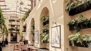 An indoor atrium with wooden furniture, potted plants, and artwork on the walls. - Casa del Alma Hotel Boutique & Spa (San Cristóbal de las Casas)