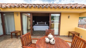 A hotel room with a bed, a wooden table with chairs, and a balcony with a tiled roof. - Casa del Alma Hotel Boutique & Spa (San Cristóbal de las Casas)